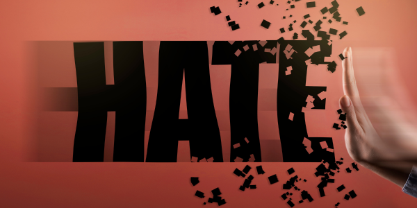 A raised hand breaks apart the word “HATE,” symbolising the rejection and prevention of hate crime